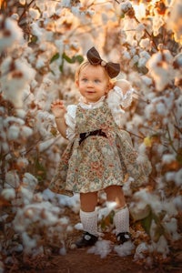 a little girl standing in a cotton field