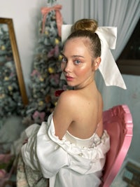 a woman in a white dress sitting on a pink chair